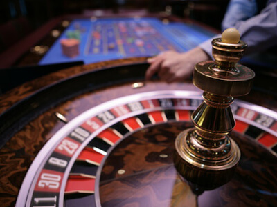 Ein Croupier dreht in einem Casino die Roulettscheibe.